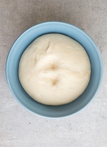 the dough has risen, in a blue bowl