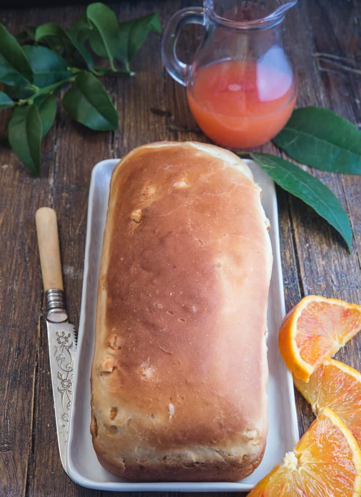 orange bread on a white board with orange slices and a knife