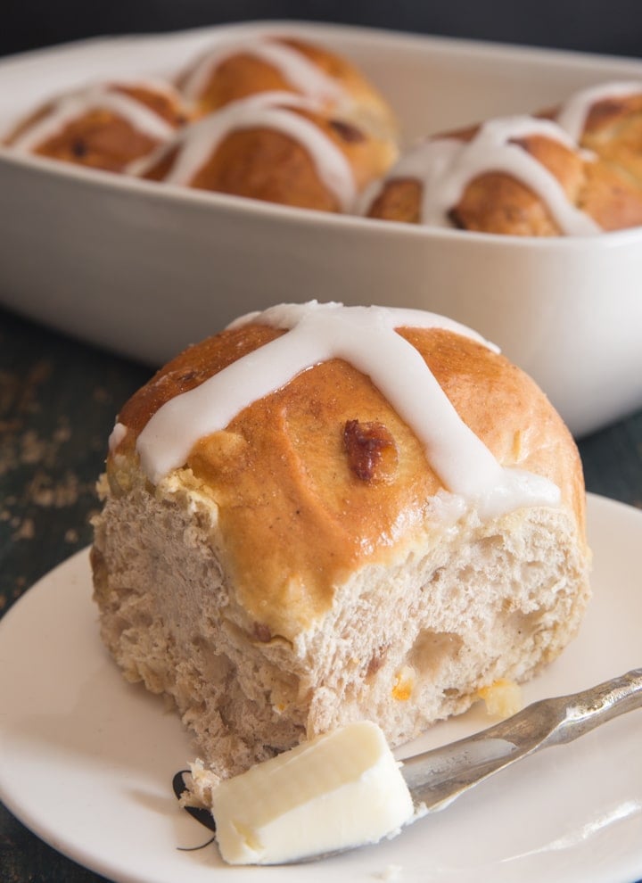 hot cross bun on a plate and the rest in a white baking dish