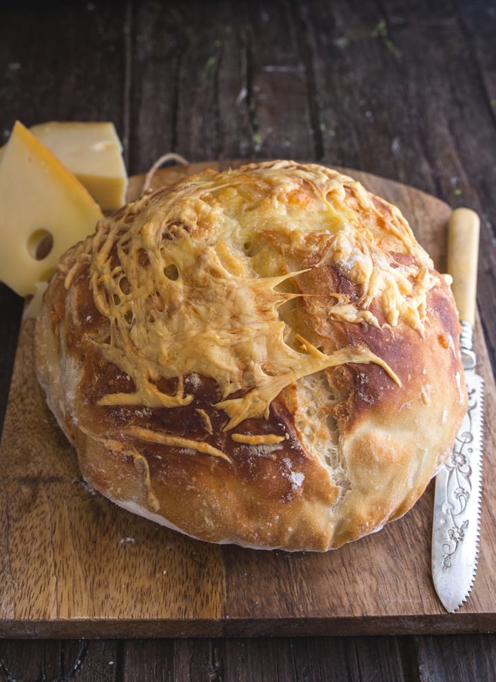 cheese bread on a board with a knife and 2 chunks of cheese