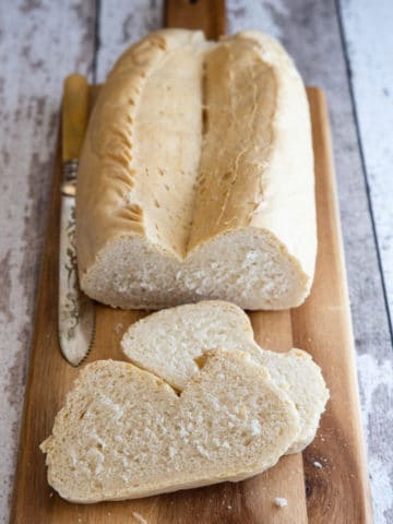 biove bread loaf on a wooden board with 2 slices and a white knife