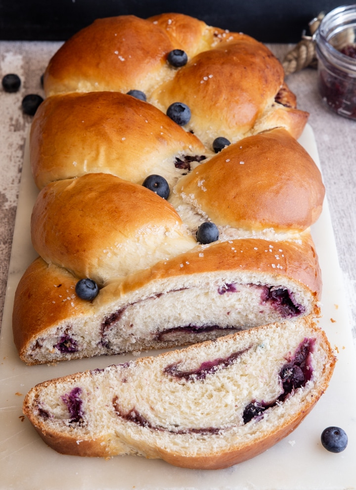 blueberry braided bread on a white board with a slice cut