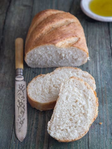 a loaf with 2 slices cut and a knife on a blue board