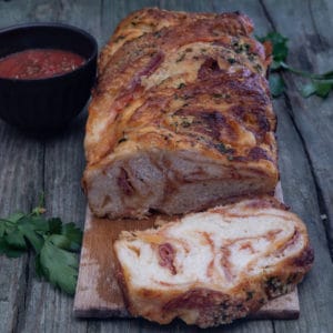 pizza babka on a wooden board with a slice cut