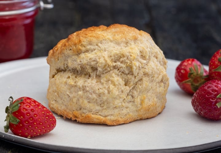 a scone on a white plate with strawberries.