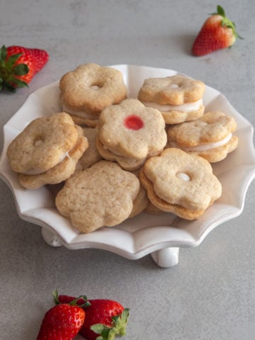 Strawberry sandwich cookies on a white plate.