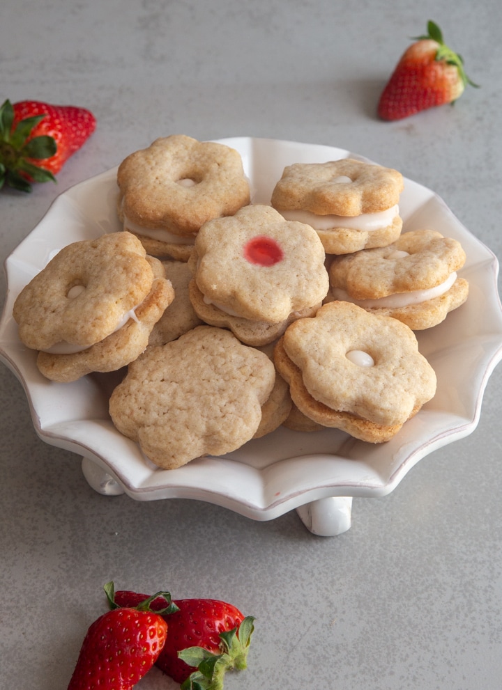 Strawberry sandwich cookies on a white plate.