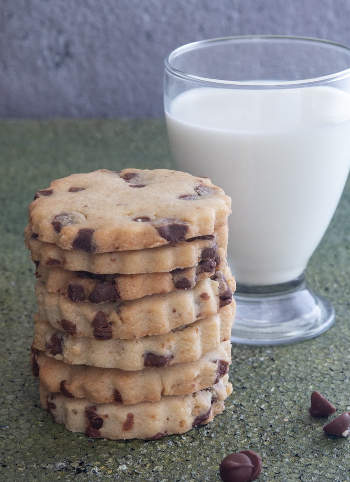 A stack of chocolate chip cookies with a glass of milk.