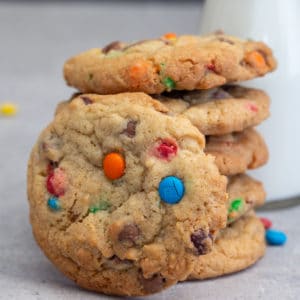 5 cookies stacked with 1 leaning against them and milk in small bottle with a straw.