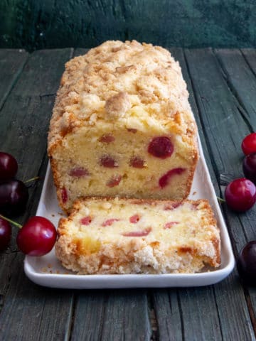 Cherry bread on a white plate with a slice cut.
