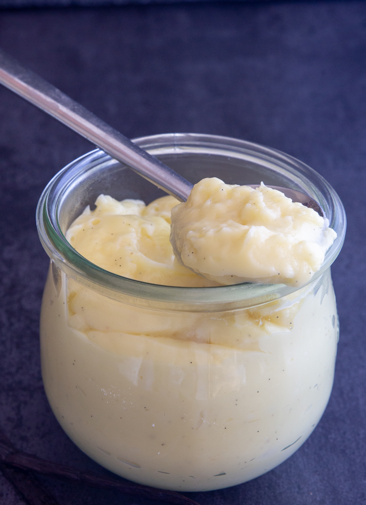 Pastry cream in a jar with some on a silver spoon.