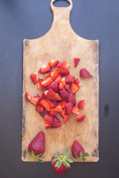 chopped strawberries on a wooden board.
