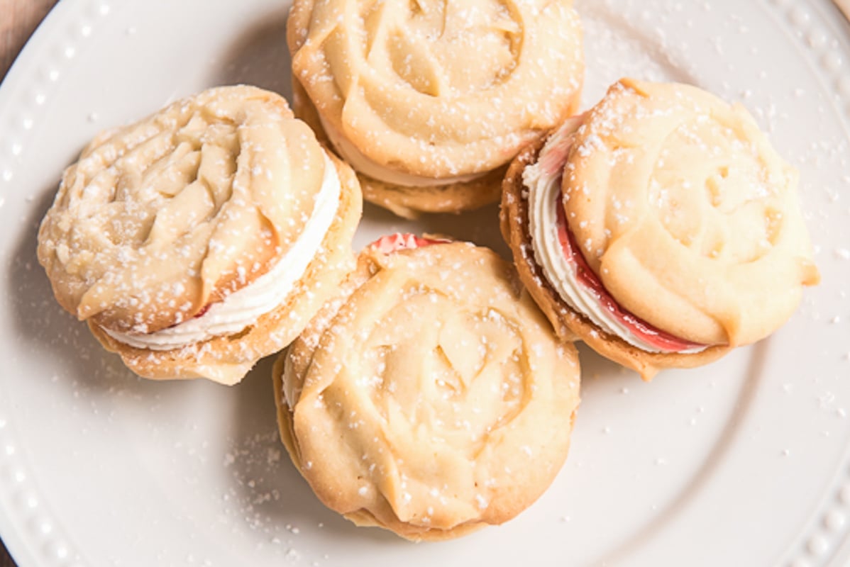 4 viennese sandwich cookies on a white plate.