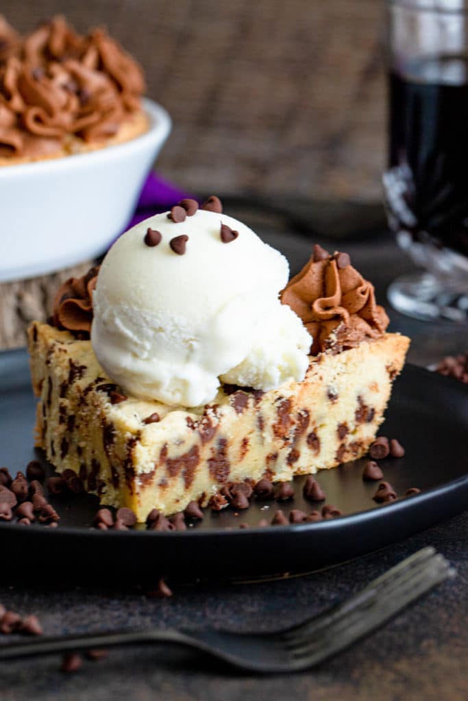 A slice of pie on a black plate with a scoop of ice cream.