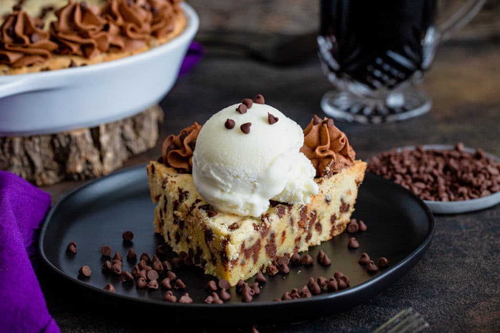 Cookie pie on a black plate with a scoop of vanilla ice cream.