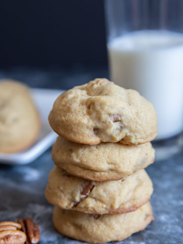 4 Cookies stacked with a glass of milk.