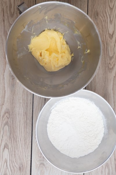 Sugar & eggs beaten into butter and whisked ingredients in a white bowl.