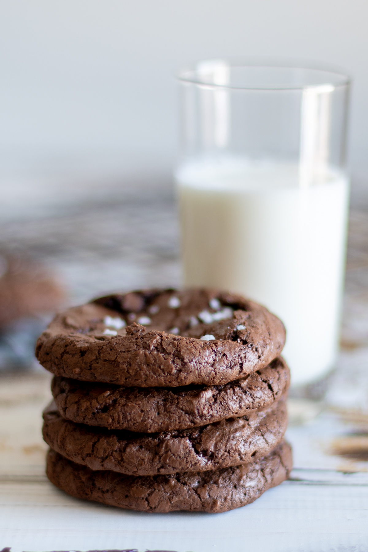 4 fudgy brownie cookies stacked with a glass of milk.