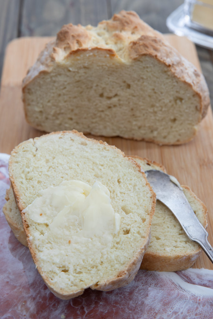 Irish soda bread loaf with two pieces sliced with butter on top. 