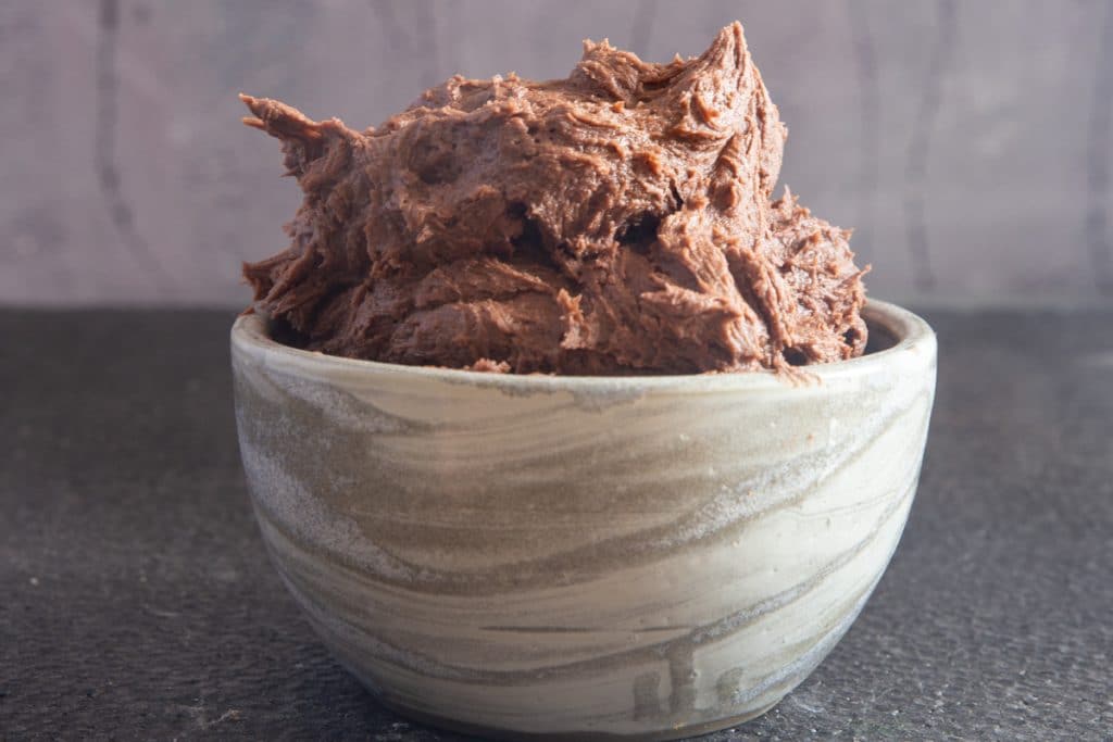 Chocolate frosting in a grey bowl.