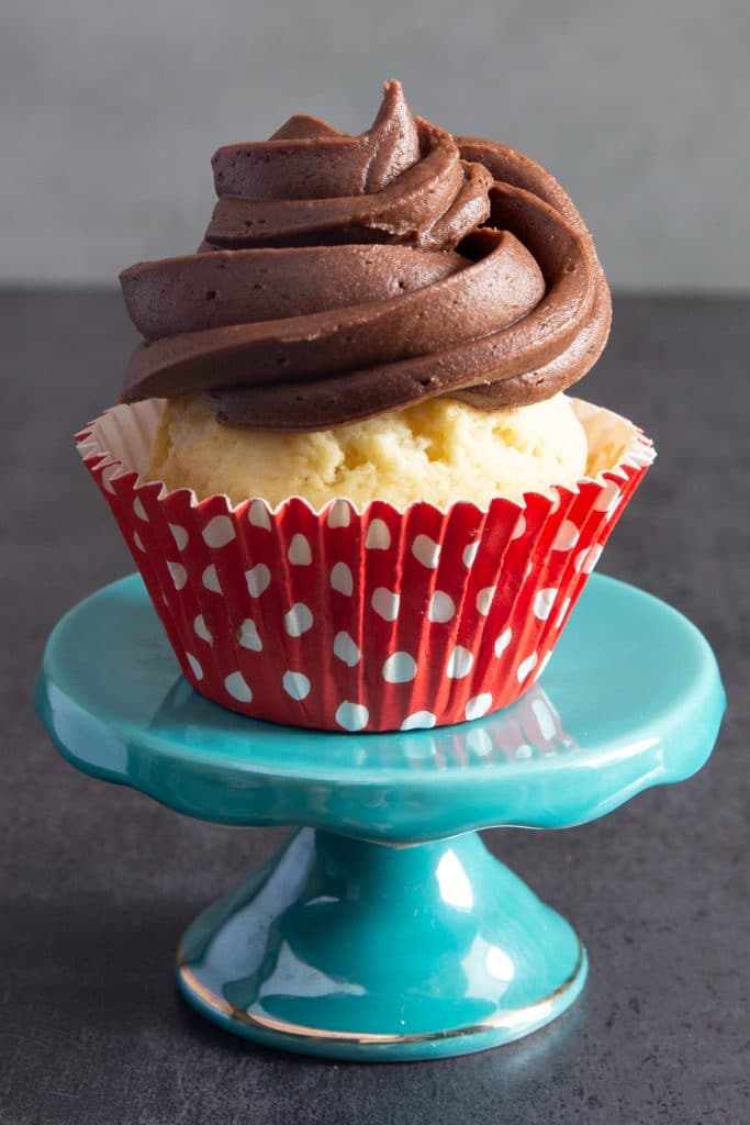 A vanilla cupcake with chocolate frosting on top.