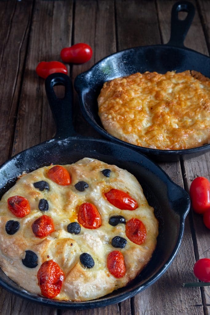 2 different types of focaccia bread in black pans.