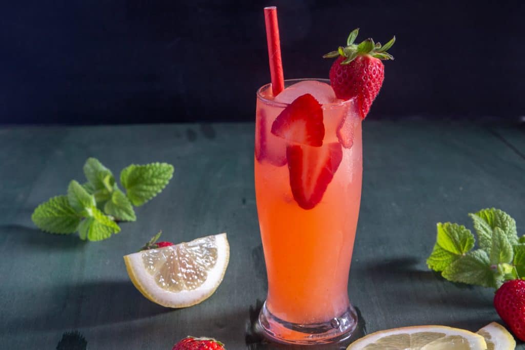Strawberry lemonade in a glass with a red straw.