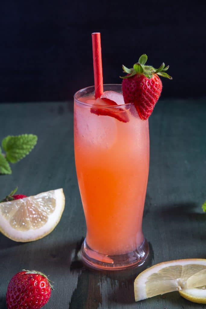 Strawberry lemonade in a glass with a red straw.