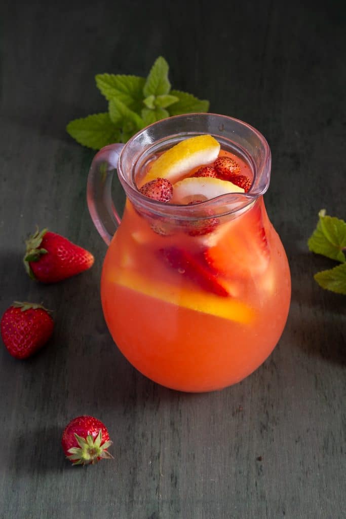 Strawberry lemonade in a glass pitcher.