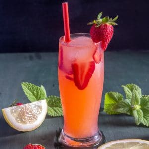 A glass of strawberry lemonade with a red straw.