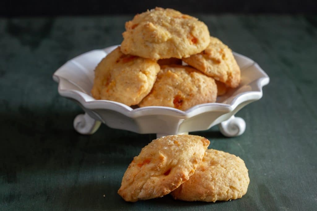 Apricot cookies on a plate and 2 on the board.