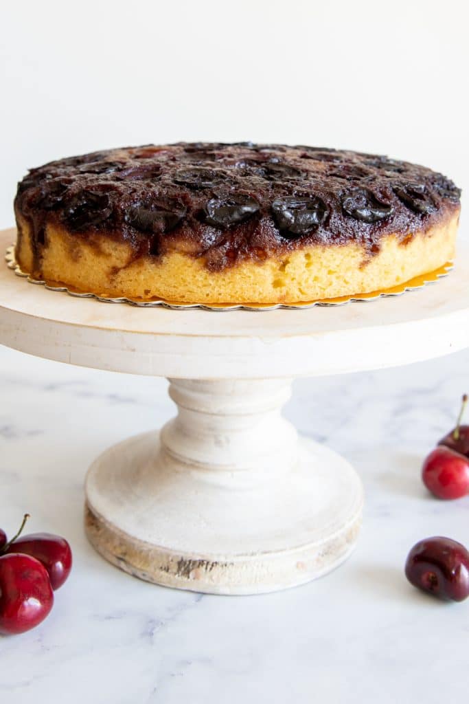 Cherry upside down cake on a white cake stand.