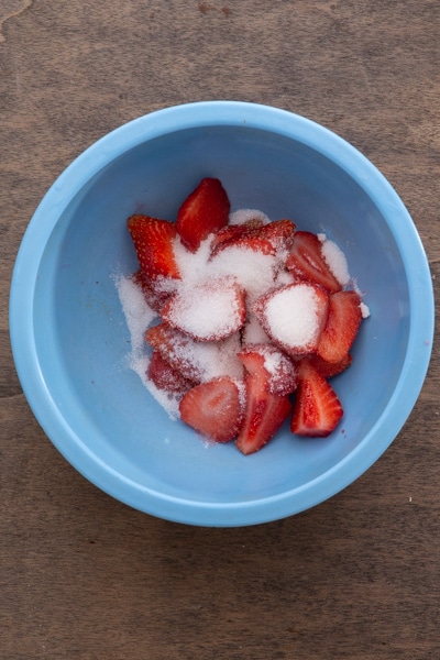 Strawberry slices and sugar in a blue bowl.