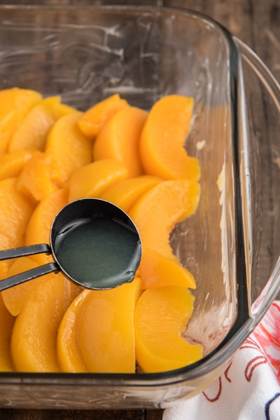 Peaches in the a glass dish and pouring the lemon juice over them.