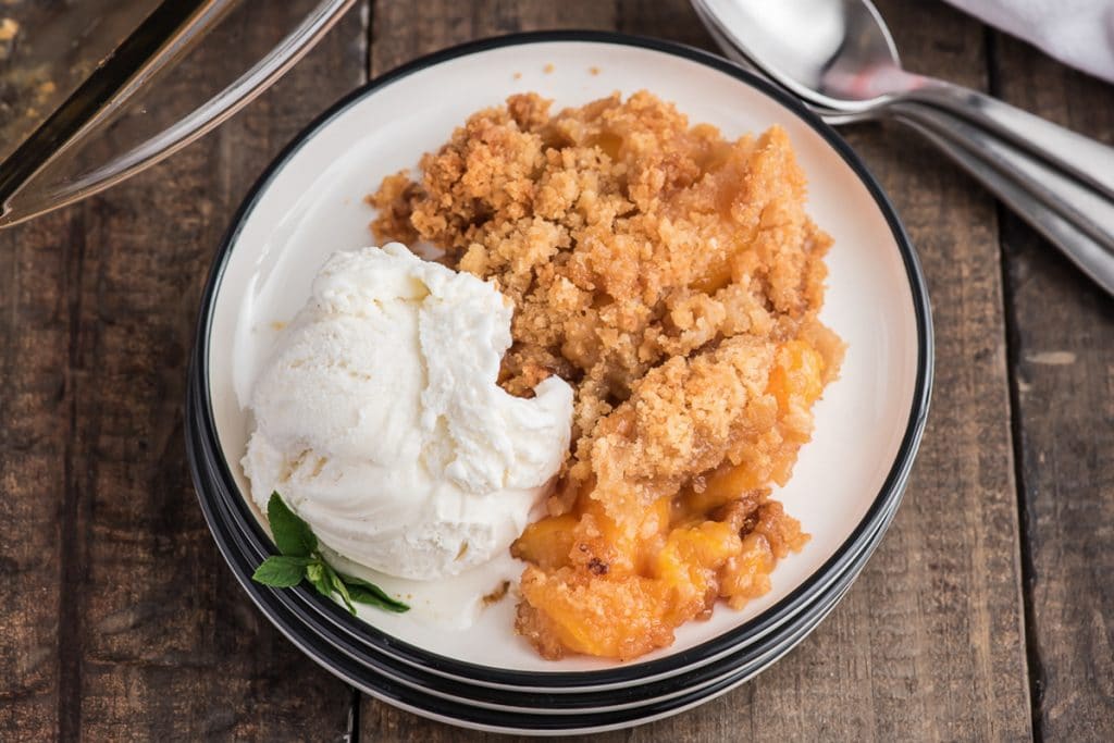 Peach crumble and ice cream on a white plate.