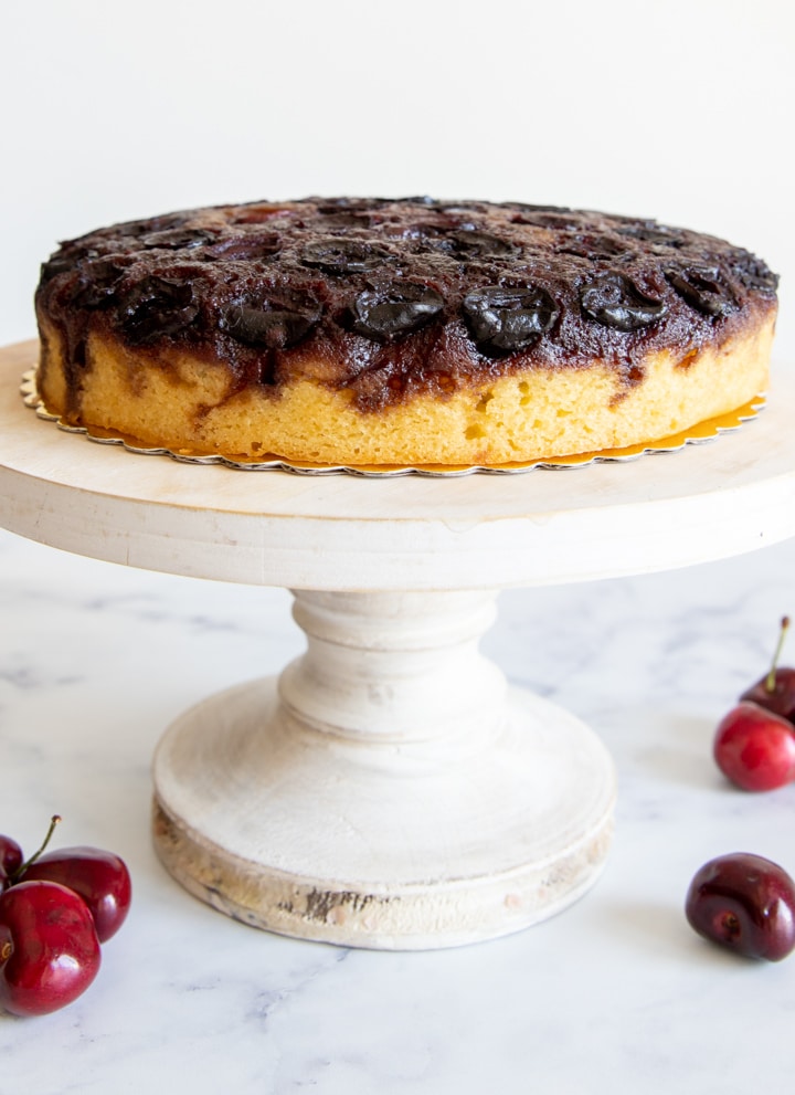 Cherry upside down cake on a white cake stand.