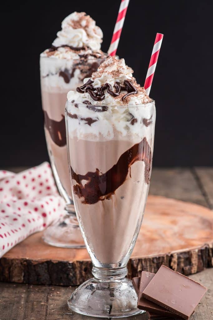 Chocolate milkshake in 2 glasses with straws.