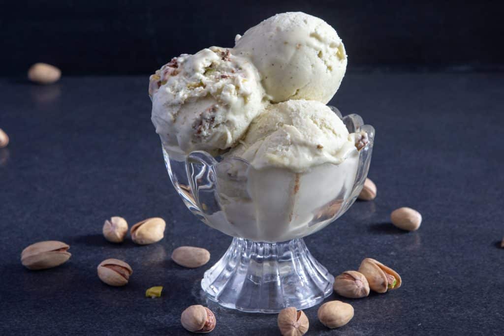 3 scoops of pistachio ice cream in a glass bowl.