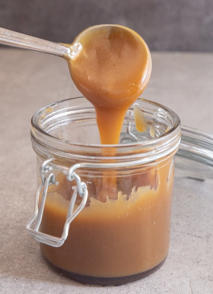 Caramel sauce in a jar and on a spoon.