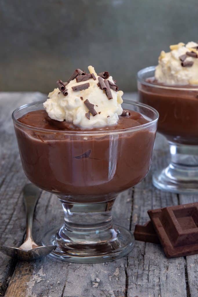 Chocolate pudding in 2 glasses with a spoon.