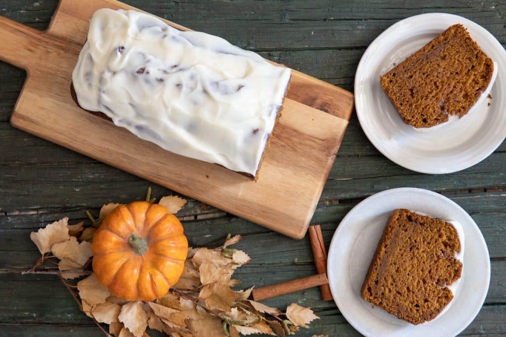 Pumpkin bread with 2 slices cut on a white plates.