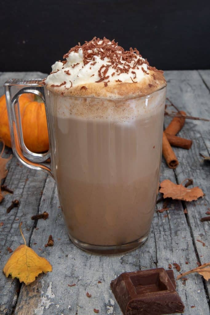 A glass with the coffee inside and whipping cream and cocoa powder on top. 