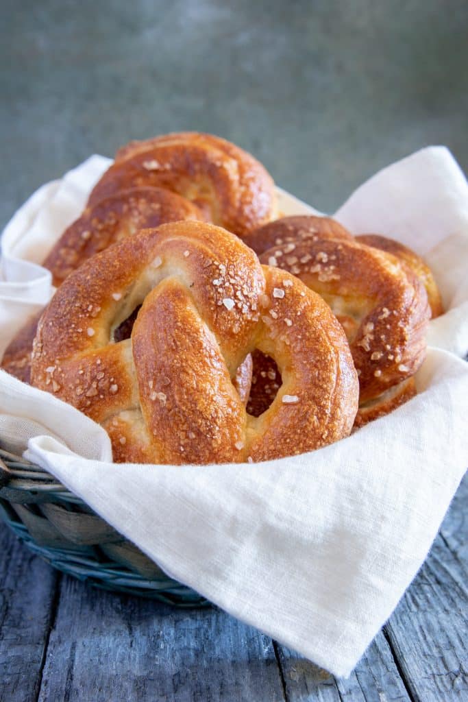Three pretzels in a basket with a white cloth.