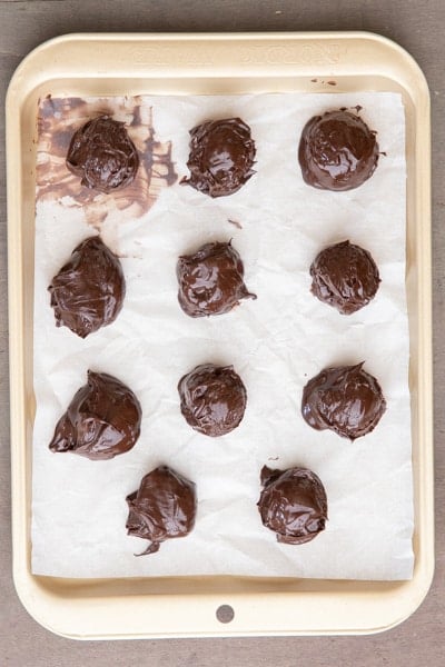 chocolate spread balls on a parchment paper lined baking dish.