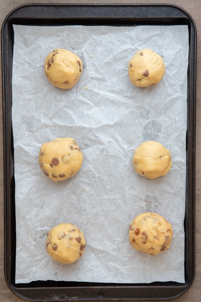 cookie dough made into balls on a parchment paper lined sheet.