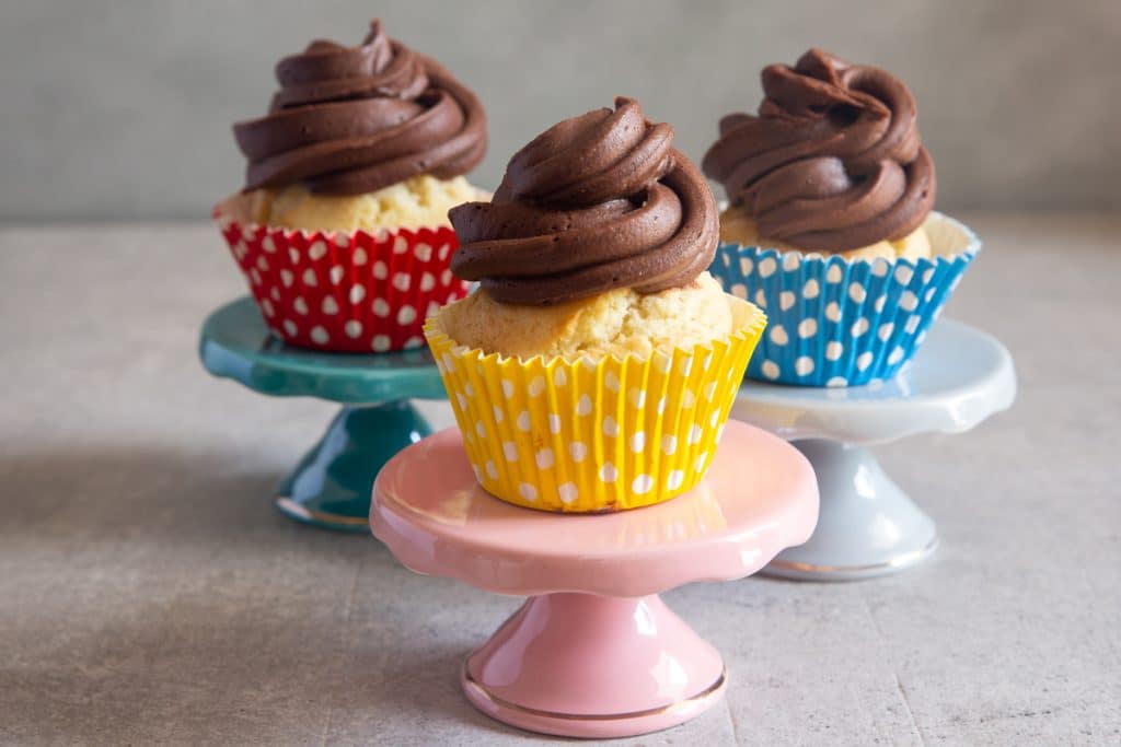 three cupcakes on three different cake stands.