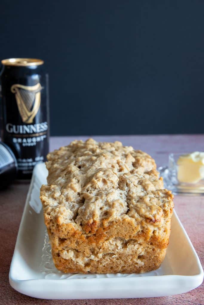Beer bread on a white plate with two cans of Guinness in the back.