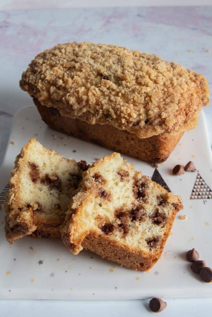 Chocolate chip bread on a white board with two slices in front.