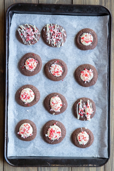 cookies with white chocolate and crushed peppermint candy on a cookie sheet.
