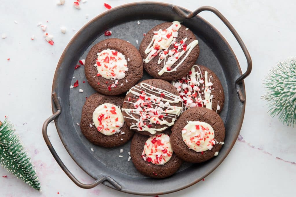 Cookies on a black plate with crushed peppermint candy around it.